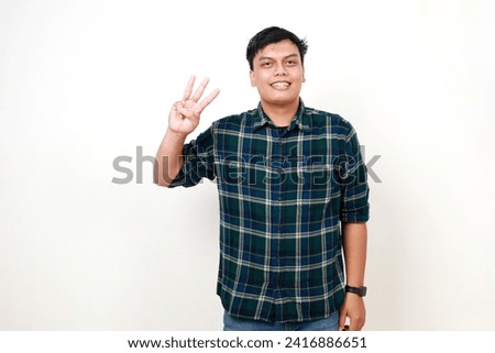 Happy young adult Indonesian man standing while showing three fingers. Isolated on white