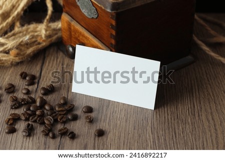 Empty business card mockup with coffee beans and vintage grinder on wooden table background. Mock up for branding identity. Blank template for your design.