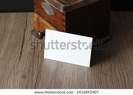 Empty business card mockup with vintage coffee grinder on wooden table background. Mock up for branding identity. Blank template for your design.