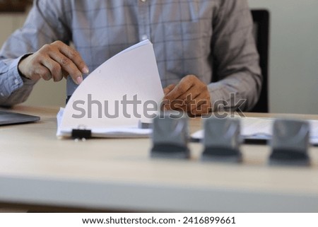 Businessman working on paperwork and stamping approvals, signing documents.