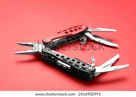 Compact portable multitool on red background, closeup