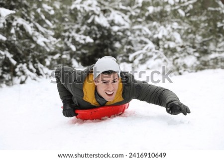 Happy man sledding outdoors on winter day. Christmas vacation