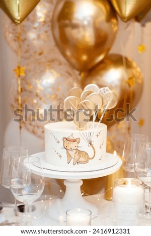 Decorated party table. Birthday cake with handpainted image of a little cat holding golden ballons