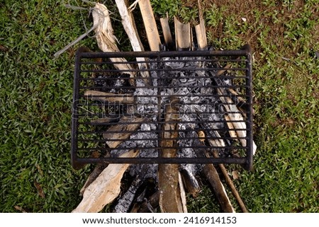 A picture of remaining firewood, ash, and grill from camping place above the ground