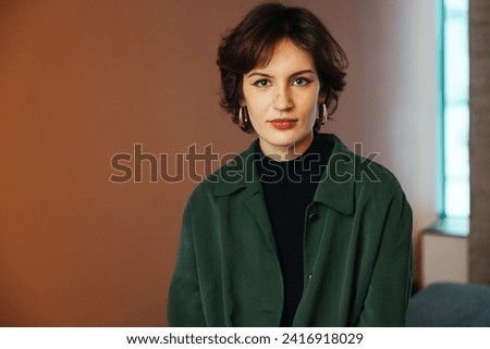 Confident young woman, poses in her modern, newly owned apartment. A headshot profile picture of a millennial female looking directly at the camera, Concept of diversity in a modern office Royalty-Free Stock Photo #2416918029