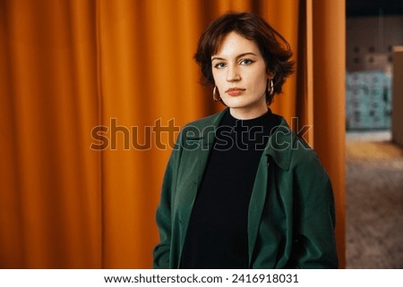 Confident young woman, poses in her modern, newly owned apartment. A headshot profile picture of a millennial female looking directly at the camera, Concept of diversity in a modern office Royalty-Free Stock Photo #2416918031