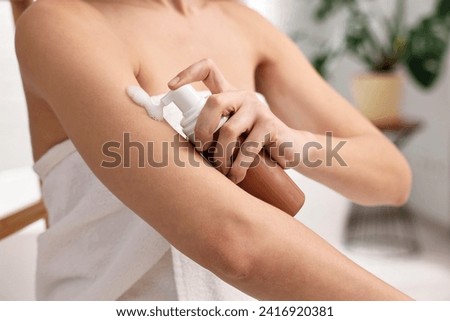 Woman applying self-tanning product onto arm indoors, closeup Royalty-Free Stock Photo #2416920381
