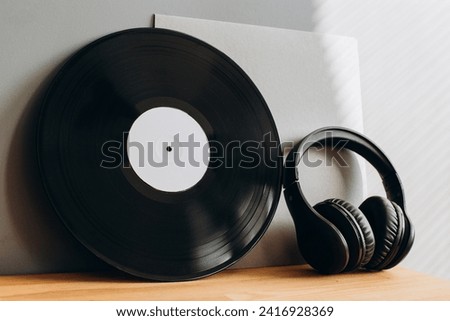 Vinyl record with paper envelope and headphones on gray background. Mockup