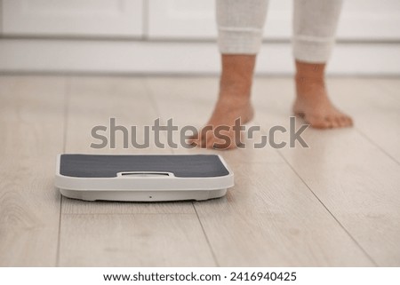 Menopause, weight gain. Woman standing on floor indoors, focus on scales Royalty-Free Stock Photo #2416940425