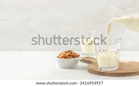 pouring nut milk into cup. lactose-free vegan drink. dairy free milk drink. Long banner format. copy space for text. Royalty-Free Stock Photo #2416954917