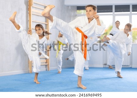 Little children in kimono standing in fight stance during group karate training