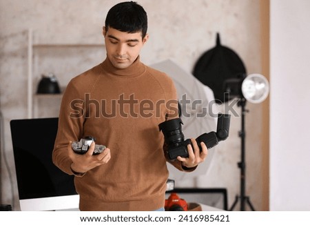 Young male photographer with cameras in studio
