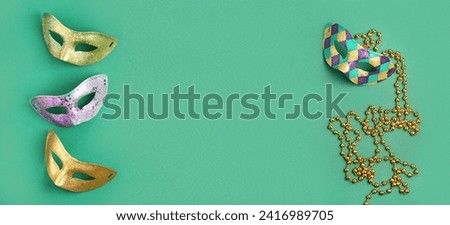Carnival masks and beads on green background with space for text