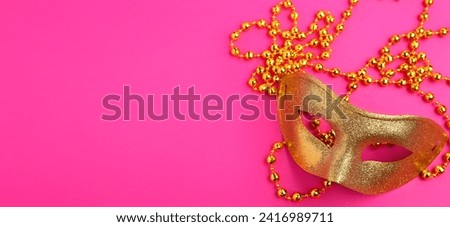 Golden carnival mask with beads on pink background with space for text