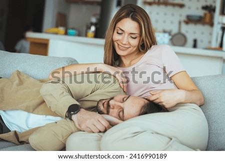 Young couple at their cute home, embracing and bonding in sofa. Enjoying weekend at home together. Cozying up during quality time. Shot of a happy couple relaxing together on the sofa at home