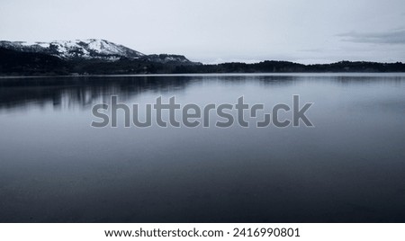 Long exposure shot of the lake at sunrise. Panorama view of the mountains and forest reflection in the water surface in an early morning with fog.  Royalty-Free Stock Photo #2416990801