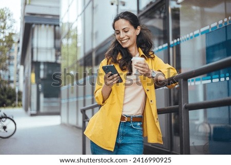 Shot of a fashionable young woman using her cellphone while walking through the city. Beautiful mid adult woman walking and texting message on mobile phone outside business center.