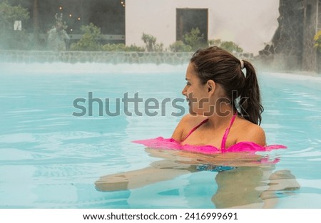 young woman with her hair tied back enjoying her holiday in a thermal water pool 