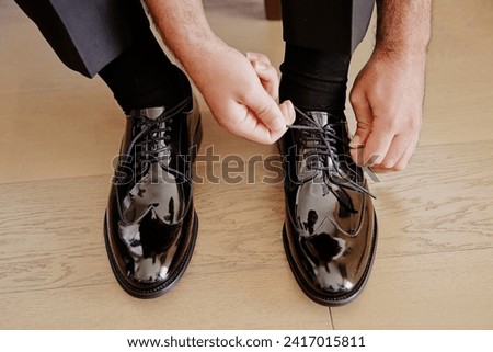 Medium closeup shot of a young groom preparing for his wedding day by tying his shoes stock photo