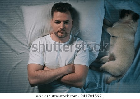 A man can't sleep because his pug dog snores. Top down view. Royalty-Free Stock Photo #2417015921