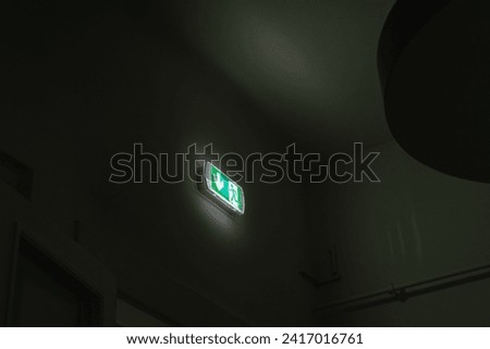 A green exit sign illuminated in the darkness of a room