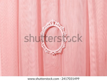 Light pastel pink tulle curtain, oval picture frame in the middle, creative copy space, place for promotion, text.