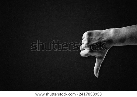 Hand Showing Thumb Down Dislike Sign in Black and White on Textured Paper Background, Copy Space