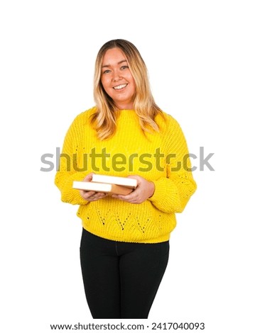 Cute young blonde female teacher holding book while wearing a yellow jumper against a white background