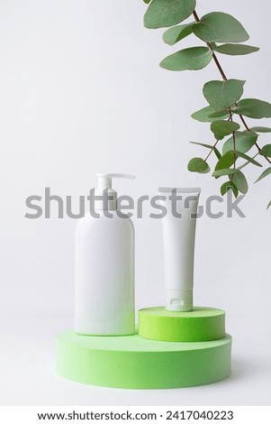  Minimalism style composition with white unbranded cosmetic tube and bottle with dropper on bright green cosmetic podium on white background. Cosmetic sale and promo banner, copy space for your design