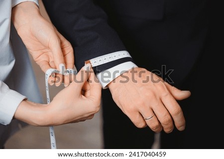 Taking measurements on man sleeve for sewing suit in luxury atelier classic menswear. Royalty-Free Stock Photo #2417040459