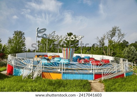 Colorful Vintage Calypso Amusement Ride with Lush Greenery Background Royalty-Free Stock Photo #2417041603