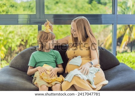 Heartwarming family moment as expectant mom and son joyfully browse through newborn baby's clothes, eagerly anticipating the arrival of a new family member