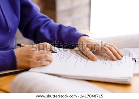 Female hands in purple sweater holding papers and signing them. Business woman working with contracts and business papers in office, hands with pen close-up, bank agreements, work contracts