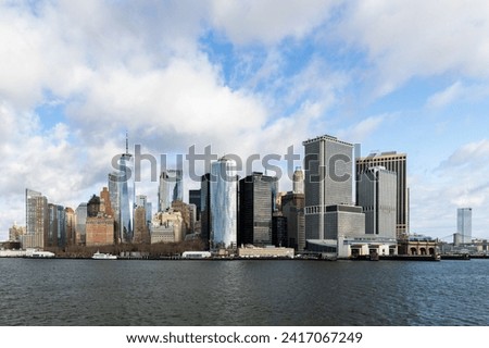 A skyline view of Lower Manhattan of New York from the bay with blue sky and clouds.