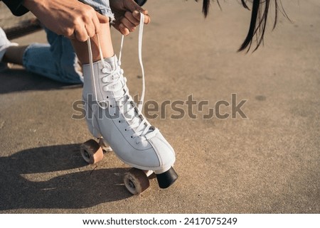 Close-up of Woman Lacing Up Quad Roller Skate. Close-up view of a young woman engaged in the process of lacing up her quad roller skate