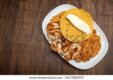 Traditional Colombian breakfast - Grilled chicken, arepa, cheese, fried egg and reheated beans with rice Royalty-Free Stock Photo #2417085957