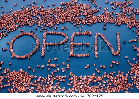 Pictures of coffee beans spread and written with words open time,concept coffee beans in darkness background.