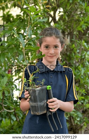 Cute Jewish girl (female age 10) planting a new tree in the garden on Tu Bishvat Jewish holiday on the 15th day of the Hebrew month of Shevat. Celebrated as an ecological awareness day.  