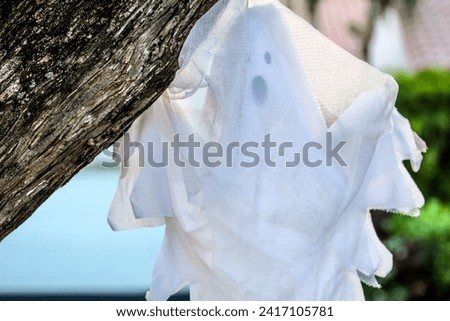 Halloween cartoon spooky ghost hanging off a tree in a residential neighborhood.