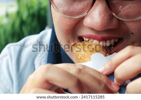 A woman wearing sunglasses bites into an ice cream pie with a confident smile, showing off her strong teeth despite the cold sensation. The image captures a moment of fun and indulgence.