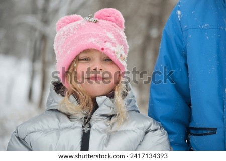 A girl in a snowy park. Photo of a child in a winter forest. Winter, winter holidays, vacations, vacations.