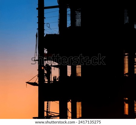 Silhouette of a Welder on a steel beam framed building at a construction site 
