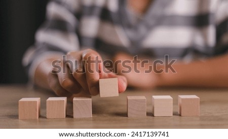 Businesswomen stack blank wooden cubes on the table with copy space, empty wooden cubes for input wording, and an infographic icon.