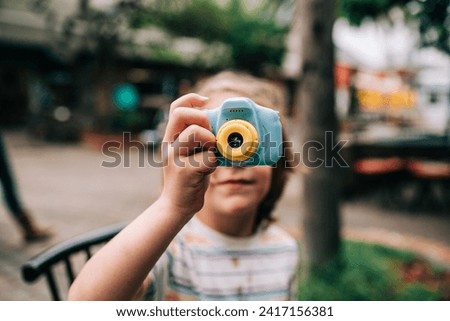 Boy in striped shirt holds up camera