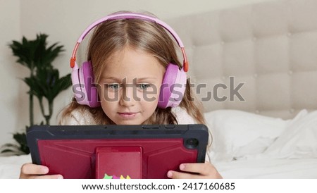 Emotion excited surprise child in headphones playing digital tablet computer home. Application for children development. Toddler watch interesting learning video, movie, online class, listen to music