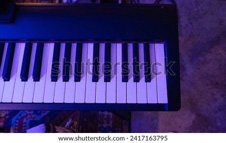 Midi keyboard in home music studio in blue neon light. Closeup of electronic keyboard. Music instruments. Piano Keys Taken From Above as a Flat Lay Image. Piano keys side view with shallow depth