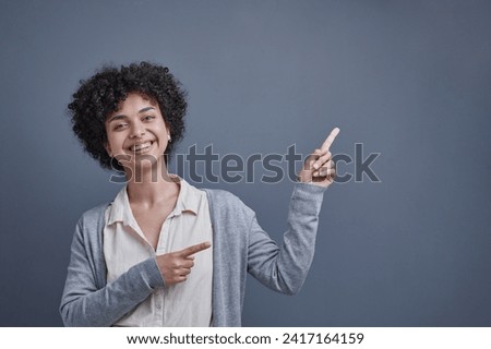 girl on a gray background smiles and shows her hand up