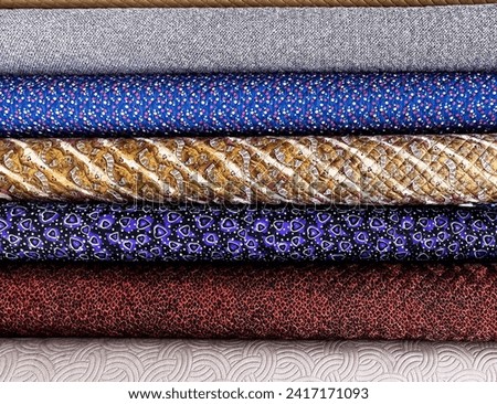 rolled samples of cloth and fabrics in different colors found at a fabrics market. Royalty-Free Stock Photo #2417171093