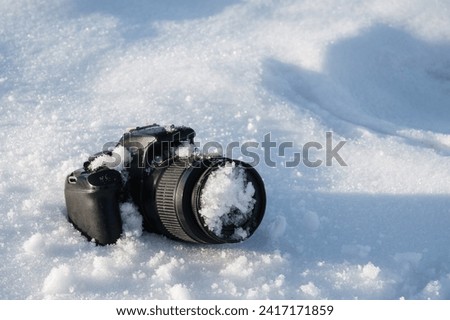 professional digital slr photo camera lies in a snowdrift in the snow in winter