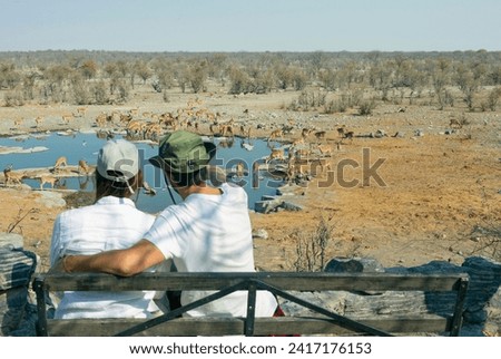 Rear view of young couple observing animals in African savannah - travel concept Royalty-Free Stock Photo #2417176153